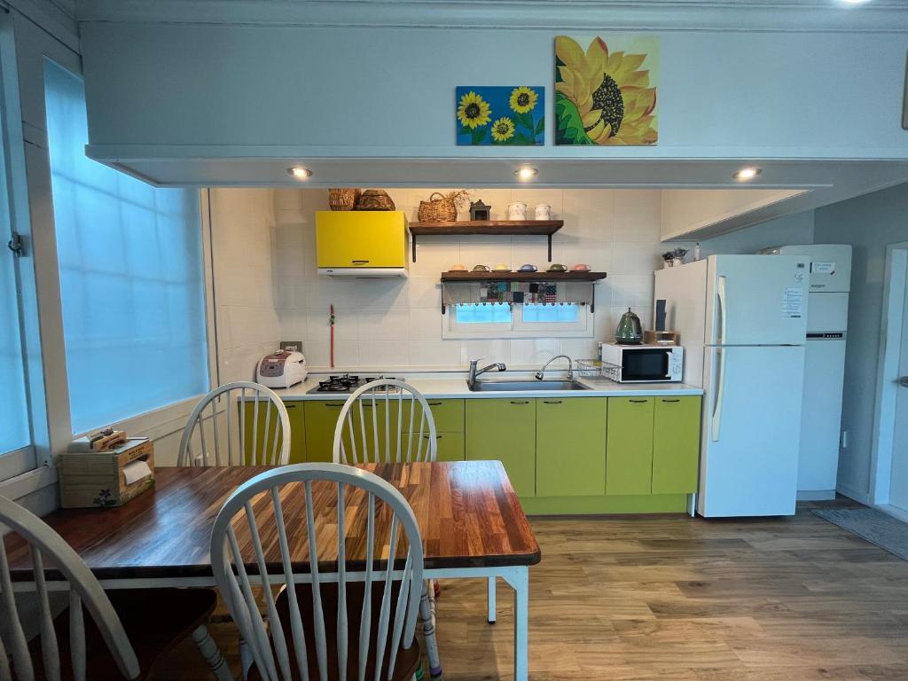 南海郡Artist and Flower Pension的厨房配有木桌和冰箱。