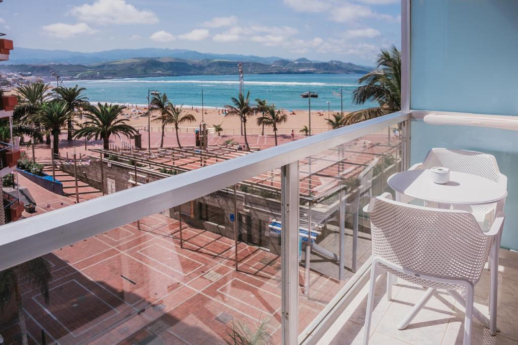 大加那利岛拉斯帕尔马斯Hotel Aloe Canteras的阳台配有桌椅,享有海滩美景。