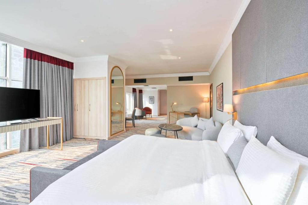 多哈Ramada by Wyndham Doha Old Town的一间带白色大床的卧室和一间客厅