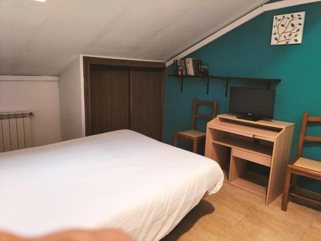 马德里休憩旅馆的一间卧室配有一张床和一张书桌及电视
