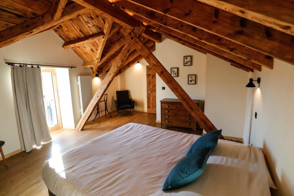 EnveitgDomaine Agricole Cotzé / Casa rural的一间带一张大床的卧室,位于一个拥有木制天花板的房间