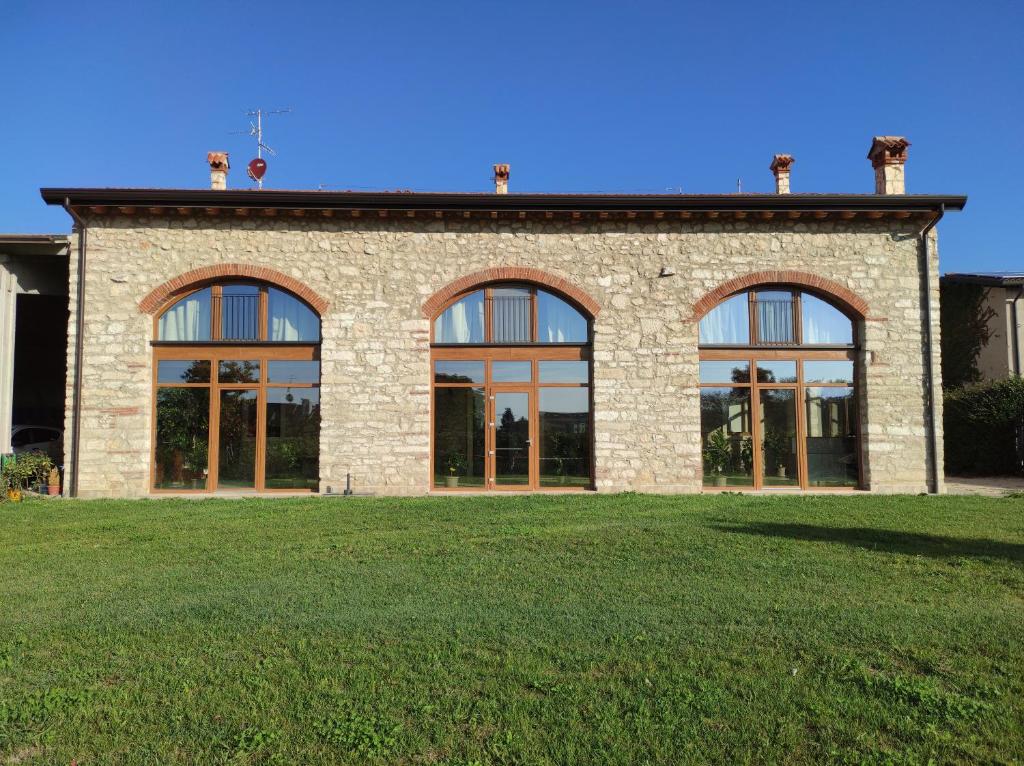 维罗纳Agriturismo Ponte Florio的砖砌建筑,在草地上设有大窗户