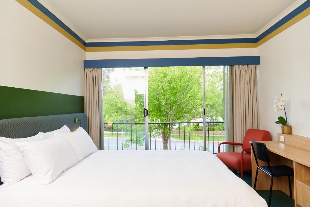 堪培拉政治家酒店 的一间卧室配有一张床、一张书桌和一个大窗户