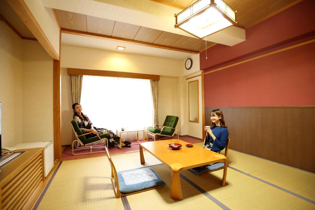 鹤冈市Kyukamura Shonai-Haguro的一间房间,配有桌子和两名坐在椅子上的女性