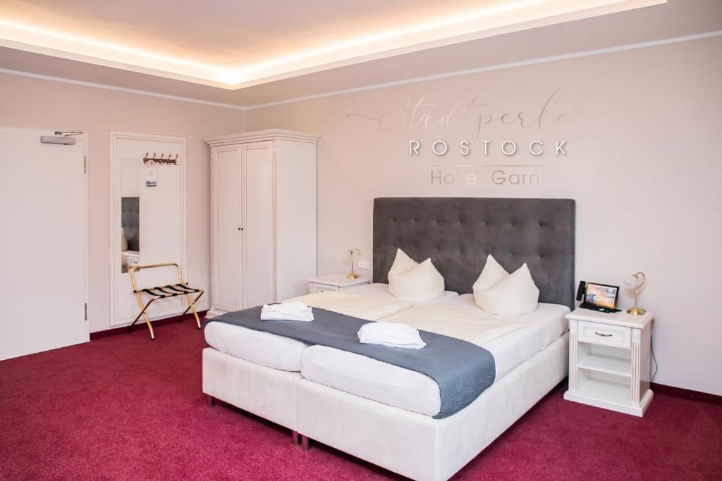 罗斯托克洛斯托克斯达特皮尔酒店的一间卧室配有一张大床,铺有红地毯