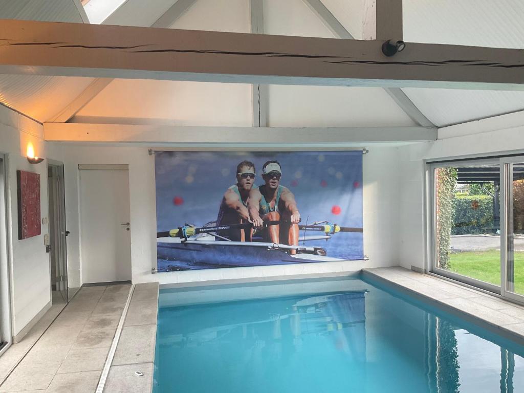 LasneLovely 1-bedroom appartement Le Joyau with indoor pool and sauna的墙上有两人照片的游泳池
