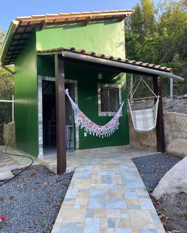 韦尔卡鲍Micro casa com vista para o Morrão - Vale do Capão的前面设有吊床的绿色建筑