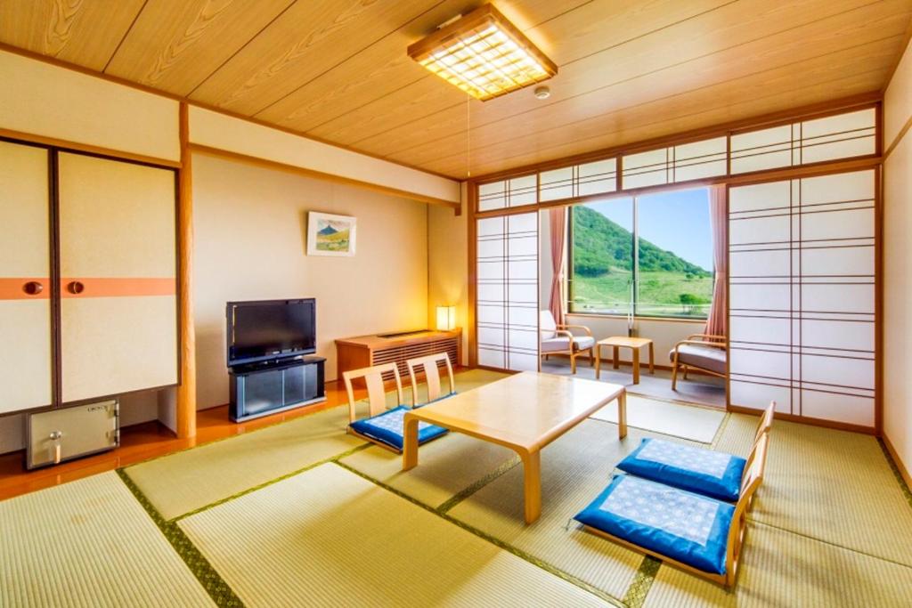 大山Kyukamura Oku-Daisen的客厅配有桌子和电视
