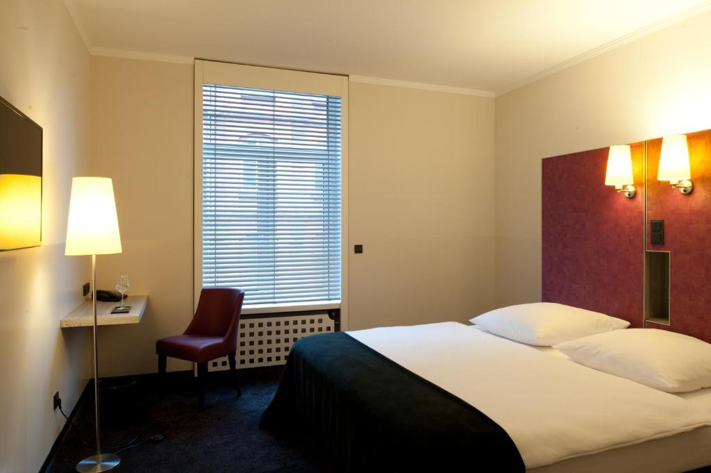 美因河畔法兰克福Hotel Topas Frankfurt City的配有一张床、一张书桌和一扇窗户的酒店客房