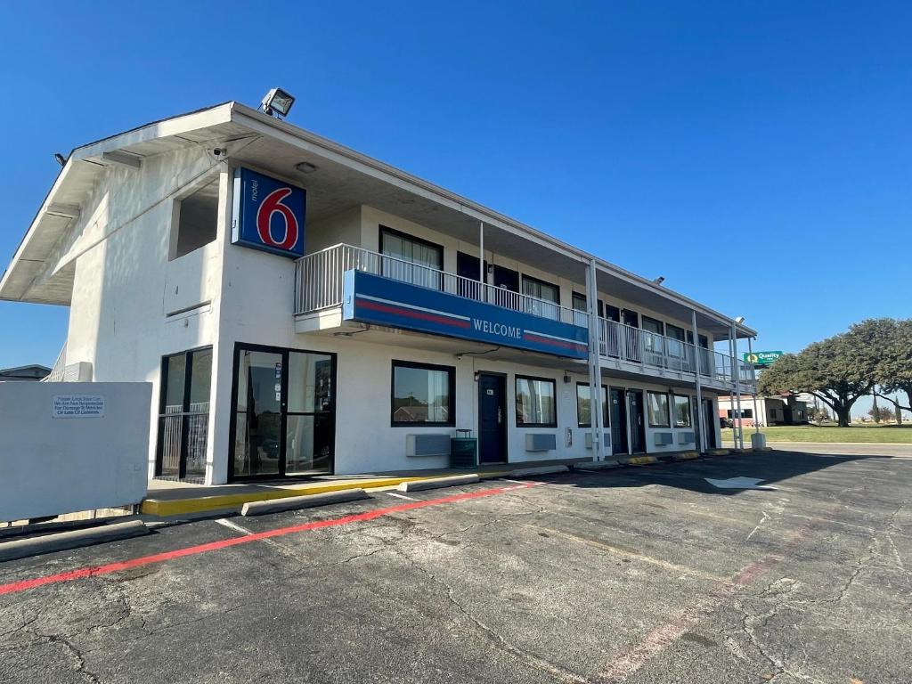 丹顿Motel 6 Denton, TX - UNT的一座白色的大建筑,上面有标志