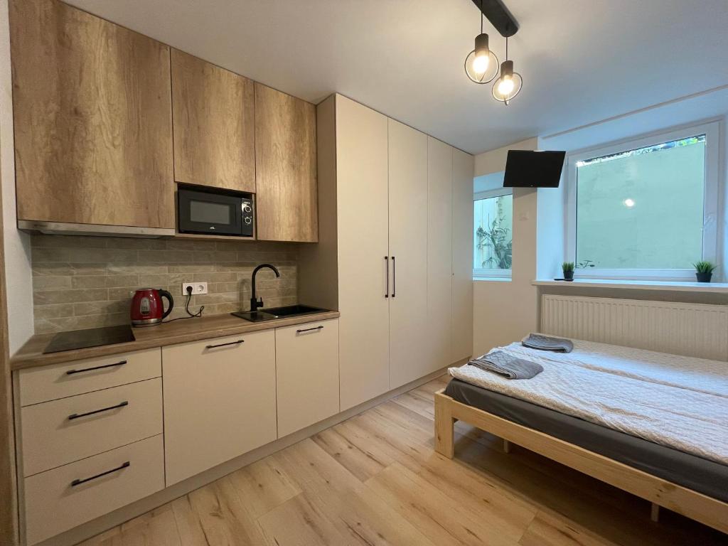 维尔纽斯Modern guest house in city center I Room 3的一间厨房,配有白色的橱柜和一张位于客房内的床