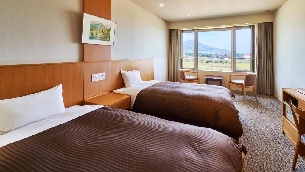真庭市Kyukamura Hiruzen-Kogen的酒店客房设有两张床和窗户。