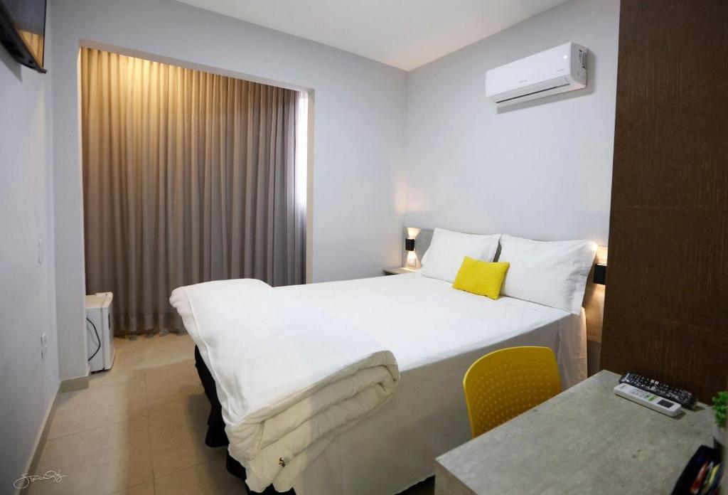 乌贝兰迪亚Aero Inn Hotel的酒店客房带白色的床和黄色枕头