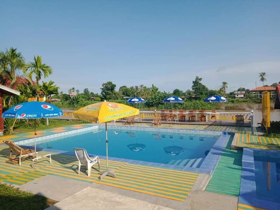 Ban DonsômPan guest house的一个带遮阳伞和椅子的大型游泳池