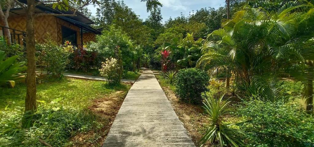班柯木Koh Mook Bamboo Bungalows的穿过花园的小路,花园内种有树木,房子里