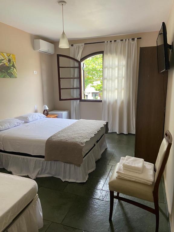 瓜鲁雅Pousada As Ondas的一间卧室设有两张床、一把椅子和一个窗户。