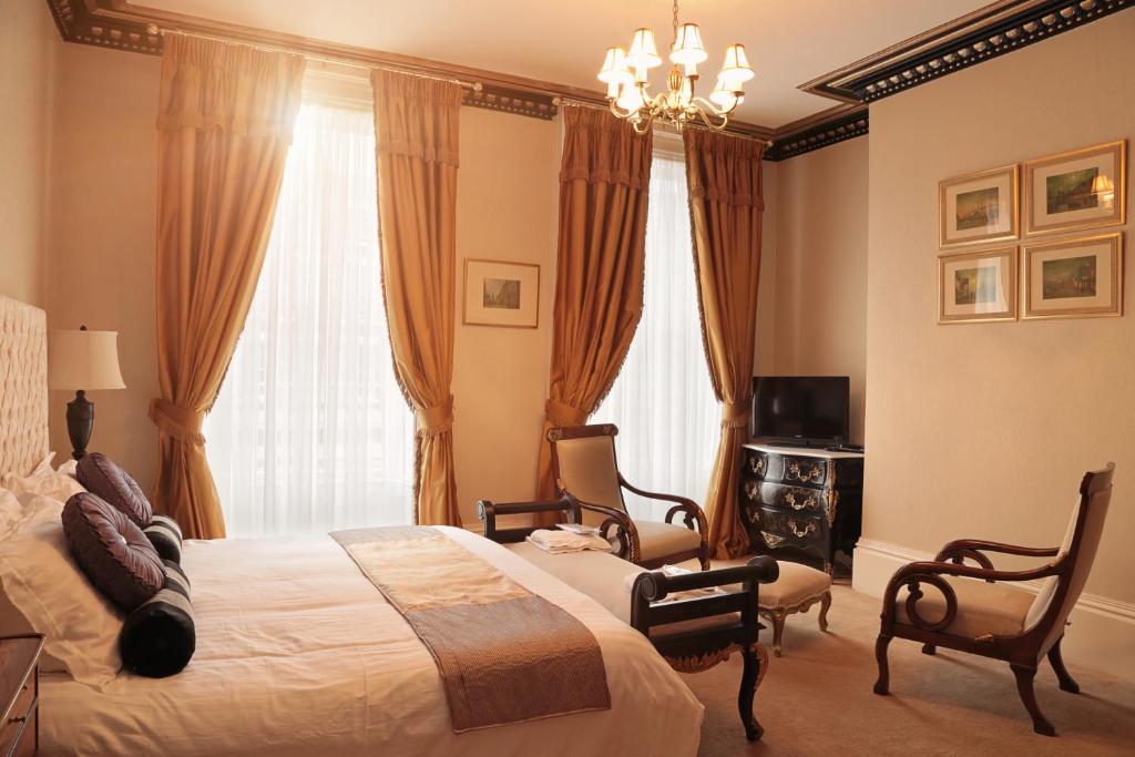 利物浦格鲁吉亚联排别墅酒店的一间卧室配有一张床、两把椅子和电视