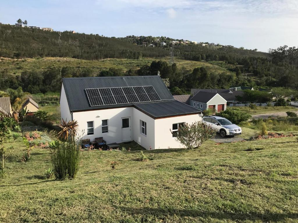 克尼斯纳Stylish Country Cottage, Solar panelled in Knysna的屋顶上设有太阳能电池板的白色房子