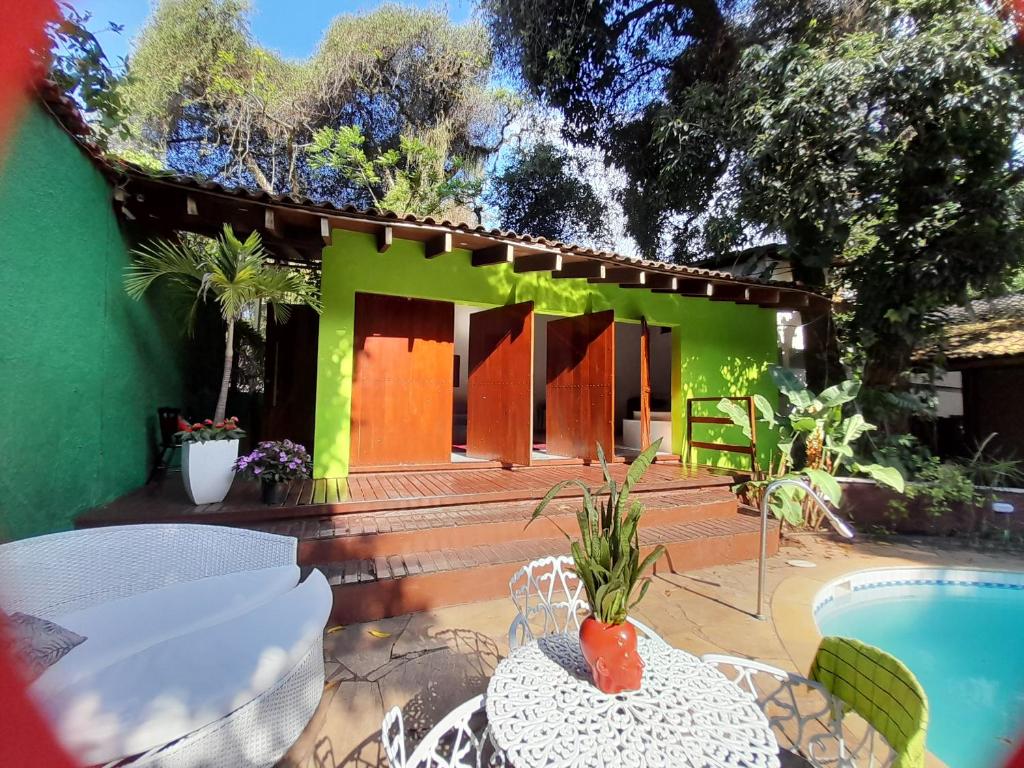 里约热内卢Pousada Solar do Redentor的绿色的房子,设有游泳池和桌椅