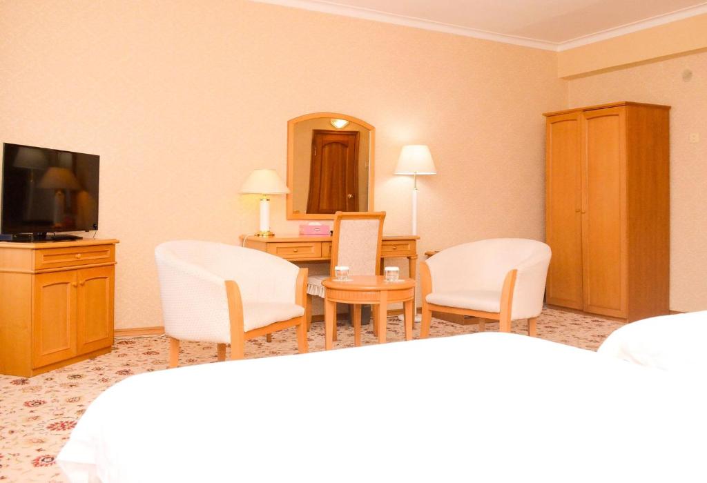 乌兰巴托Continental Hotel的酒店客房配有椅子、书桌和电视。