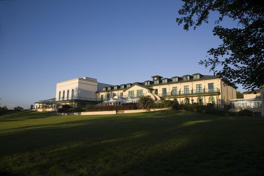 翰索经典英国溪谷酒店度假村的一座位于郁郁葱葱的绿色田野顶部的大型建筑