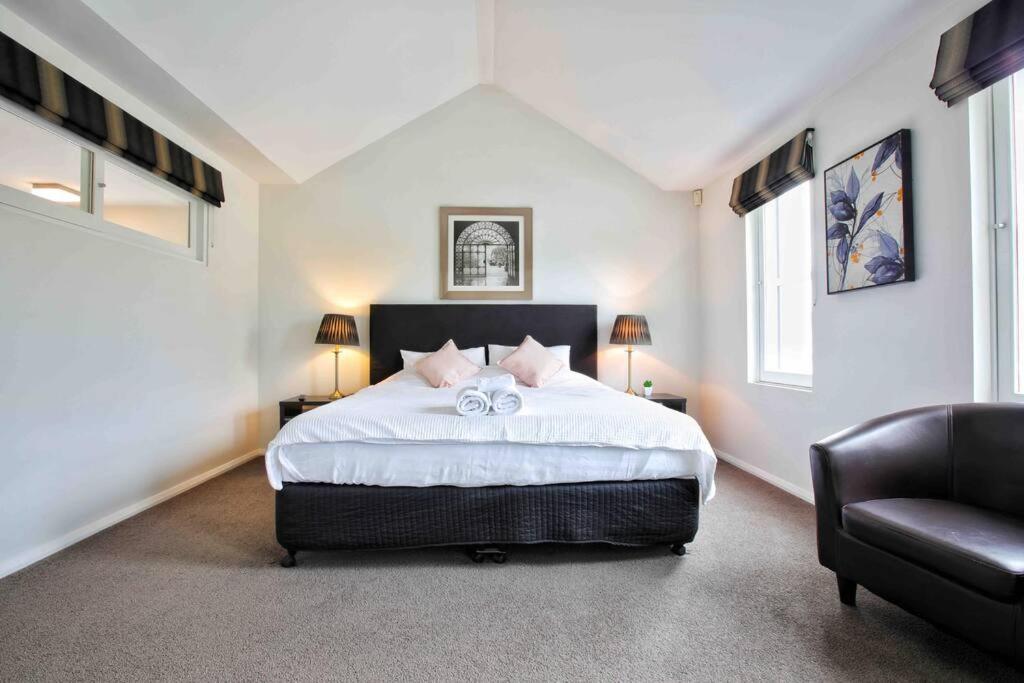 霍巴特Central Hobart - Beautiful Apartment的一间卧室配有一张大床和一把椅子