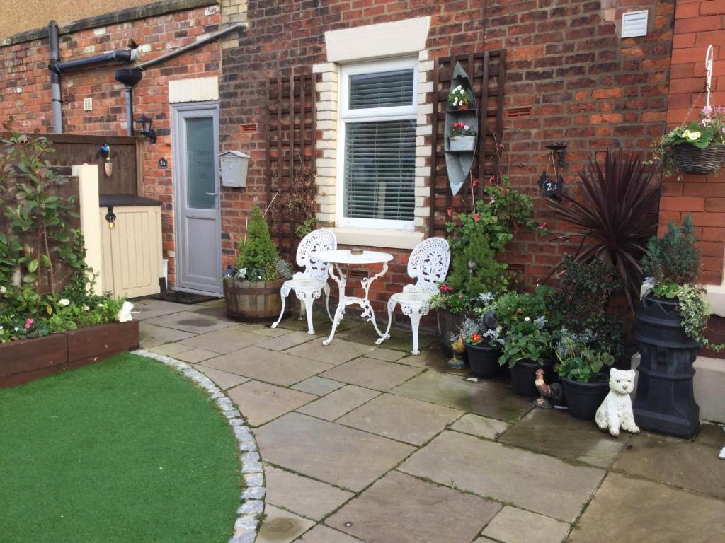 莱瑟姆-圣安妮Leafy Lytham central Lovely ground floor 1 bedroom apartment with private garden In Lytham dog friendly的庭院配有两把椅子和一张桌子,还有一些植物