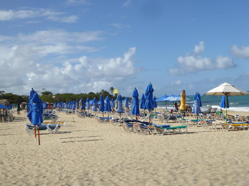 圣斐利-银港CortLang - Beach Apartments - in El Pueblito near Playa Dorada的海滩上的一组椅子和遮阳伞