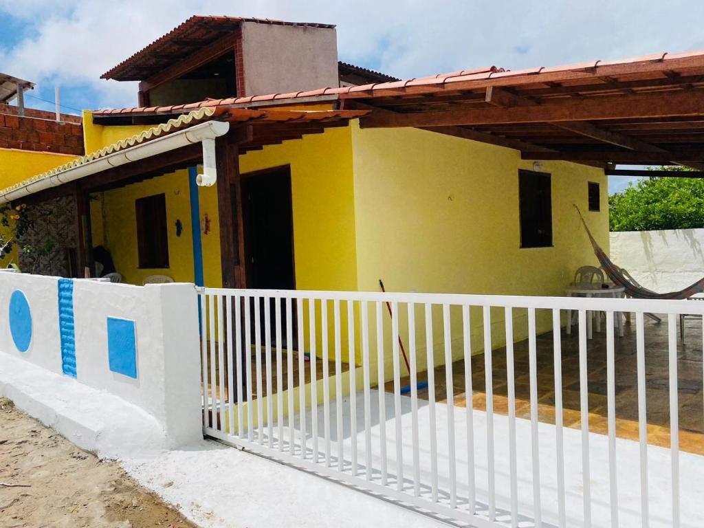 瓜吉鲁Casinha na Praia do Guajiru的前面有白色围栏的黄色房子