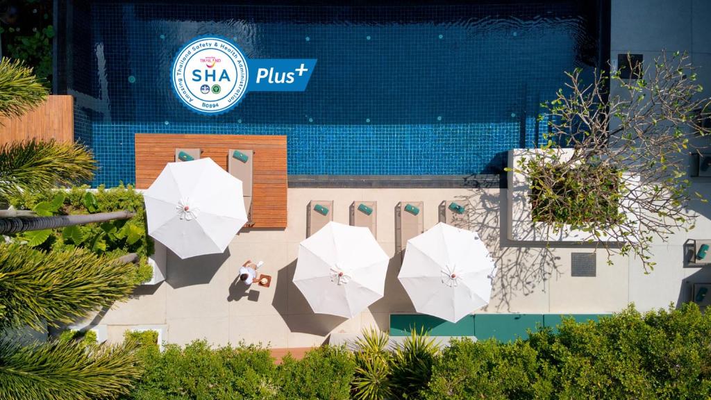 苏林海滩Outrigger Surin Beach Resort - SHA Extra Plus的大楼前的一组白色遮阳伞