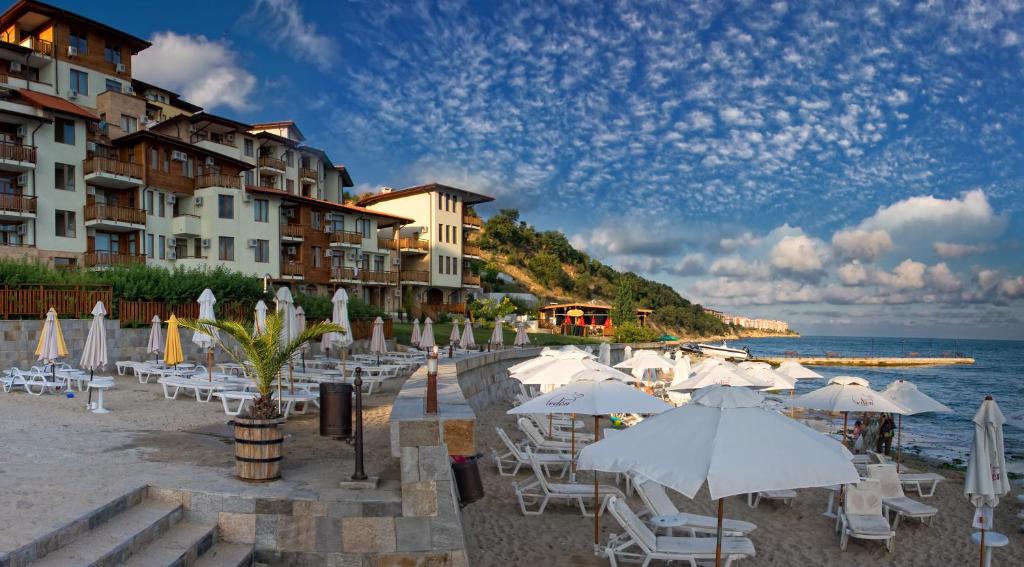 圣弗拉斯花园伊甸园大厦酒店的海滩上设有白色的遮阳伞和椅子,还有大海