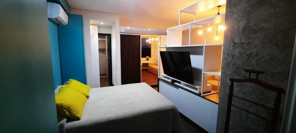 圣克鲁斯Apto en Excelente Zona con Gym Sauna y Jacuzzi的客房设有一张带黄色枕头的床和一台电视。