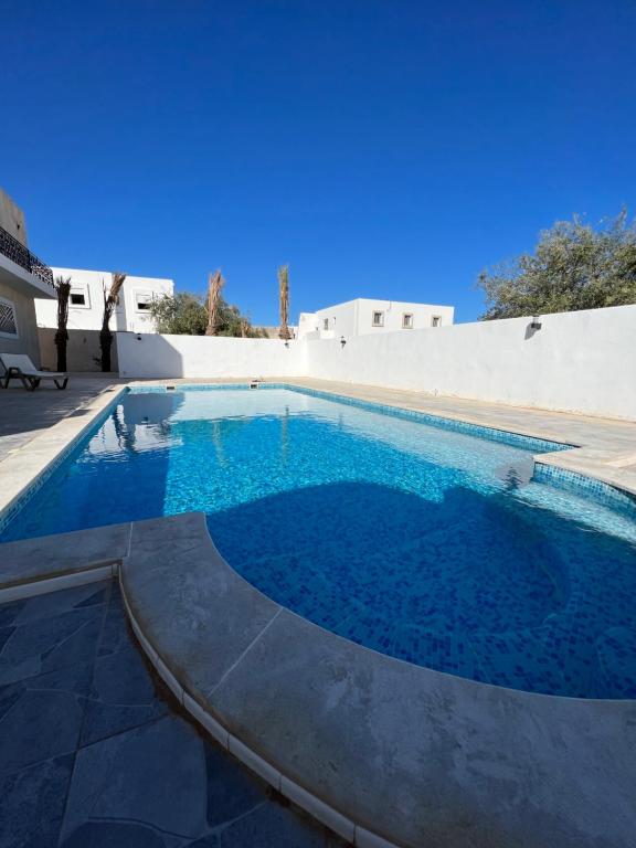 乌姆苏克Magnifique villa avec piscine sur l’île de djerba的大楼前的蓝色海水游泳池