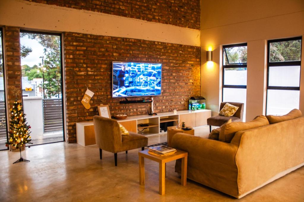 格拉罕镇Amabwe Guesthouse的客厅配有沙发和砖墙电视