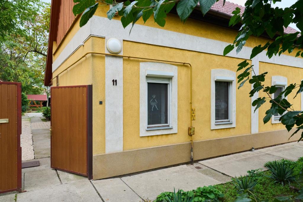霍德梅泽瓦沙海伊Kölcsey Vendégház的黄色和白色的建筑,设有两扇窗户和一扇门