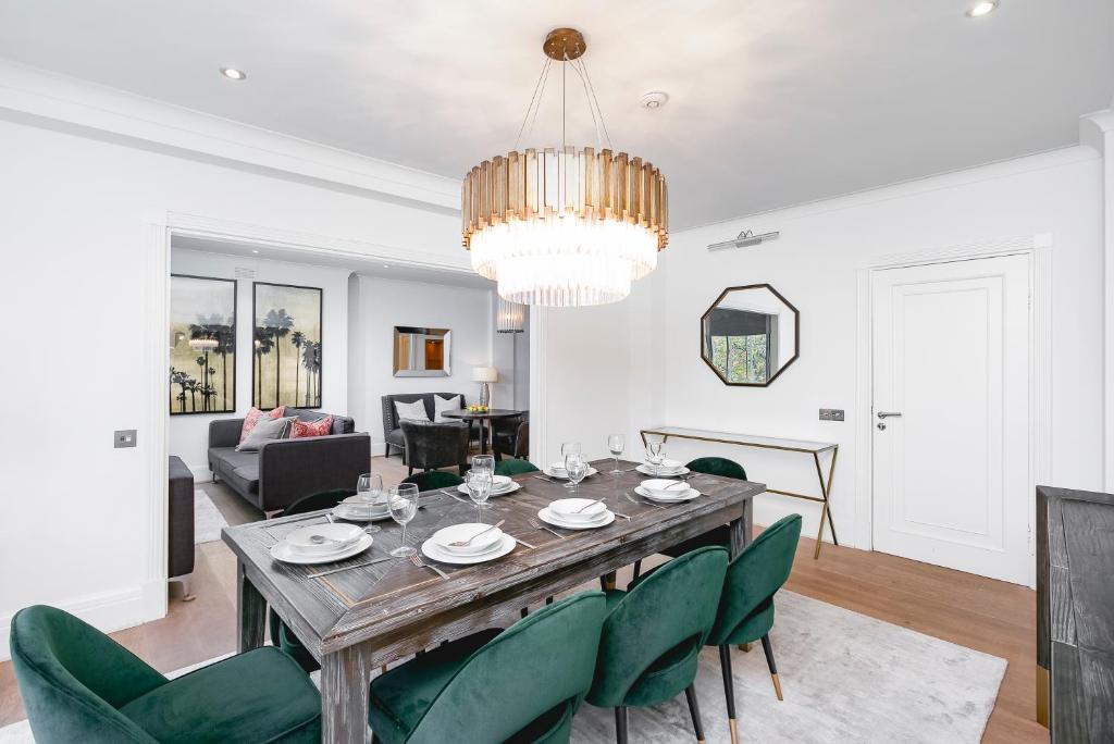 伦敦' Luxury & Spacious 4 Bed 4 Bath Apartment '的一间带桌子和绿色椅子的用餐室