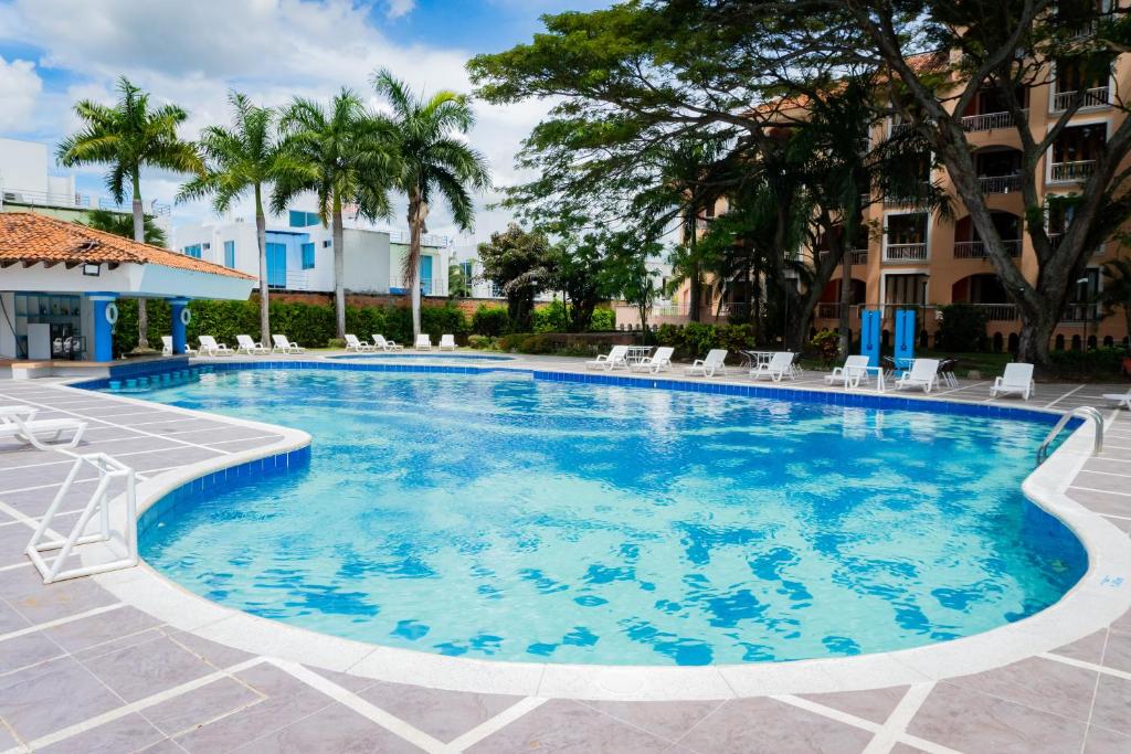 吉拉尔多特Hotel Peñon Suites的一座带椅子和树木的度假村游泳池