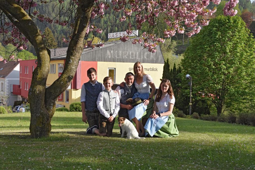 尤登堡Hotel-Gasthof Restaurant Murblick的一群人坐在树下,带着狗
