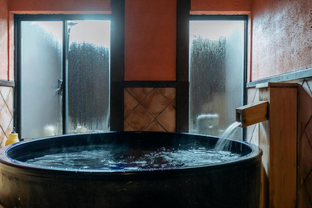 丰冈市森穗酒店的带窗户的客房内设有一个水的大浴缸