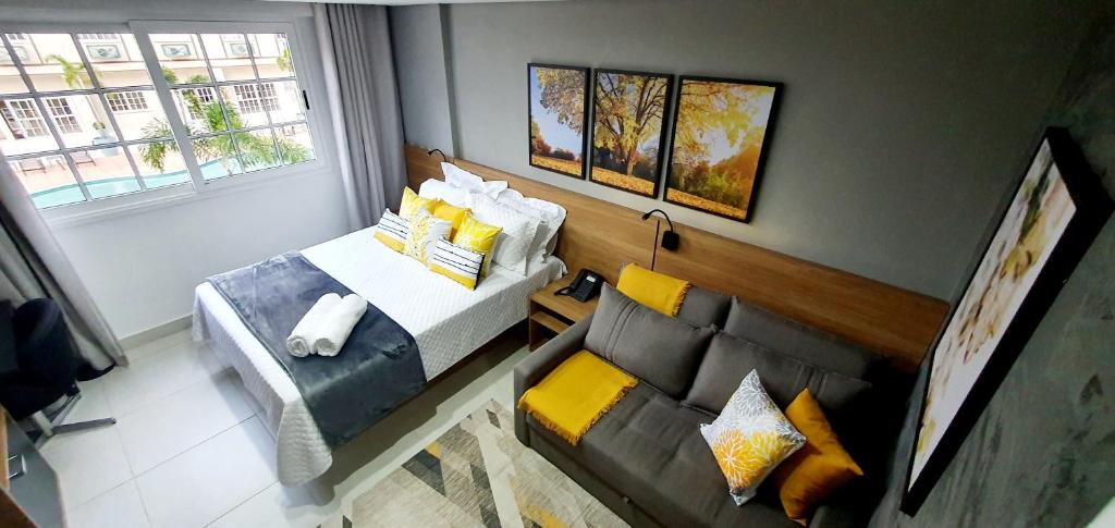 彼得罗波利斯Flat Sunshine - Granja Brasil Resort - Itaipava的客房设有床、沙发和窗户。