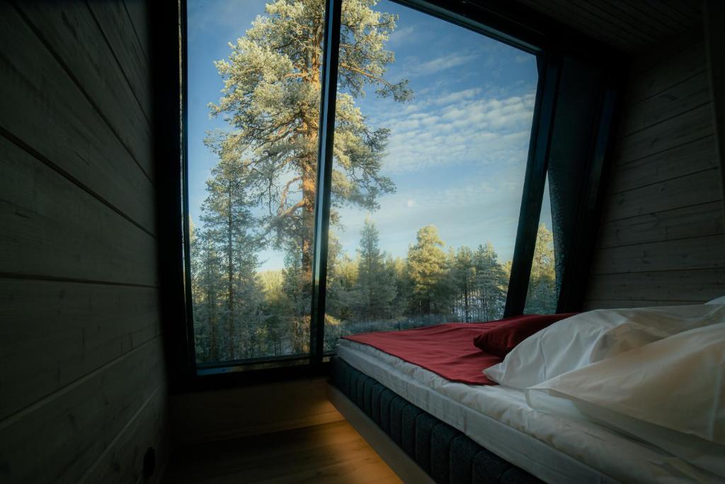 萨拉Salla Wilderness Lodges的一张位于带大窗户的房间内的床铺