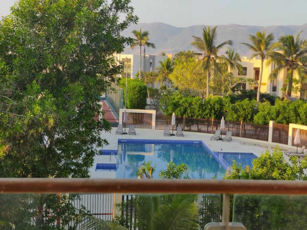 塞拉莱Hawana Salalah Laguna Studio的享有棕榈树和建筑的游泳池的景色