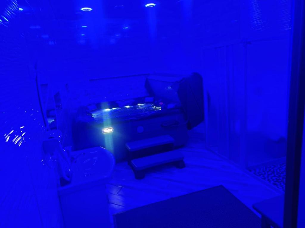 VilainiaiMieliausioji Dzekusi的一间设有卫生间和蓝色灯光的暗室