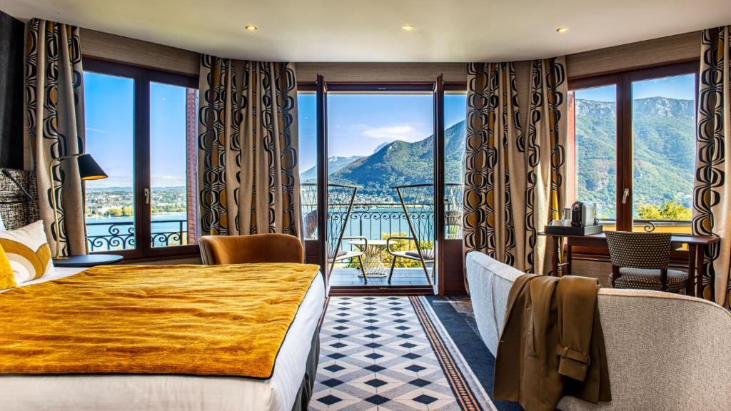 安锡Les Trésoms Lake and Spa Resort的酒店客房设有一张床和一个山景阳台