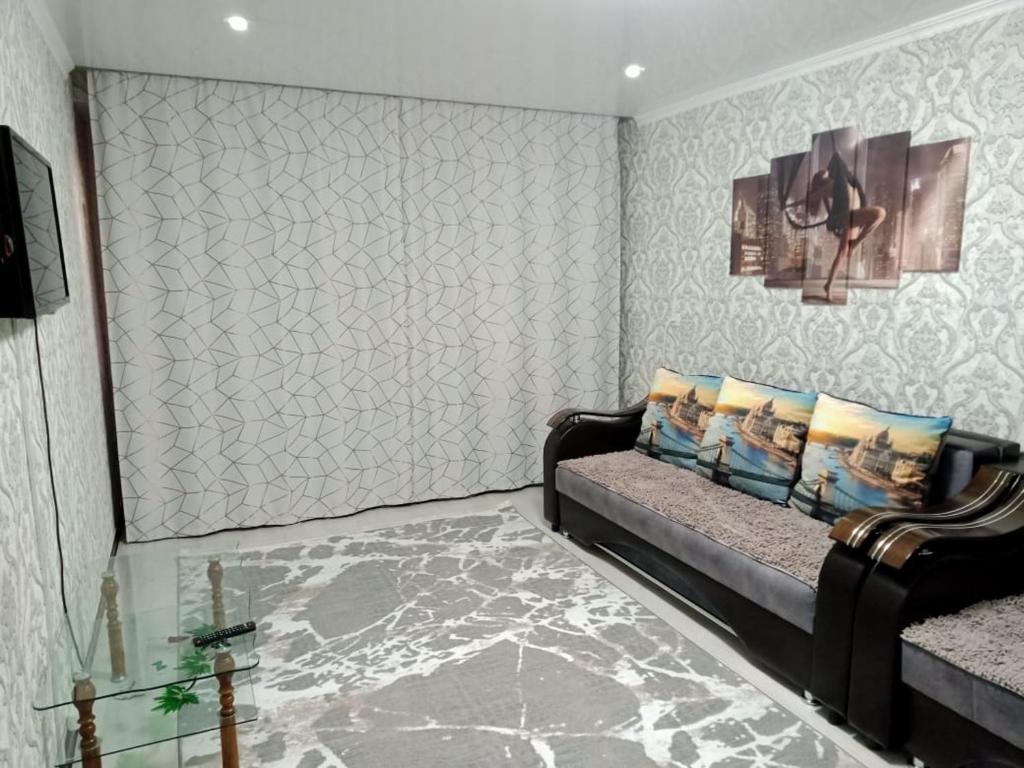 休钦斯克Квартиры的带沙发和墙壁的客厅
