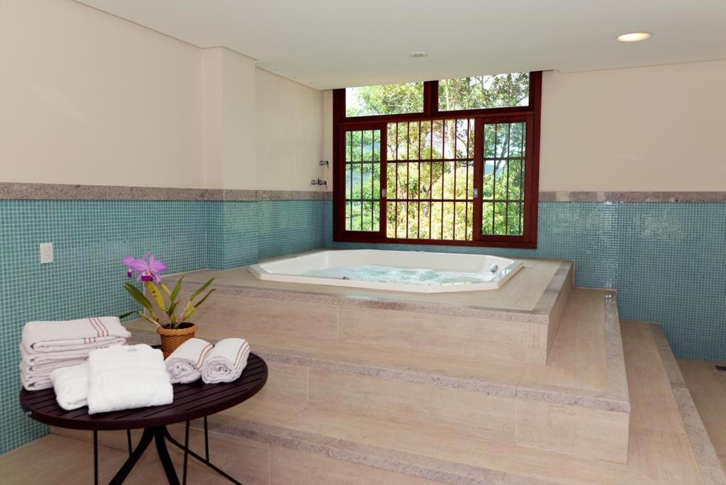 佩德拉阿祖尔Flat Pedra Azul - hospedagem nas montanhas的带浴缸和毛巾桌的浴室