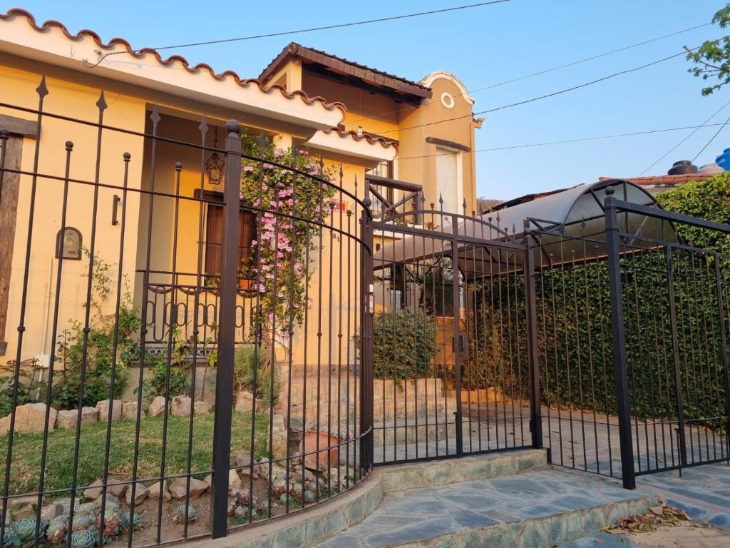 萨尔塔Hostal las Rosas的黄色房子前面的黑色栅栏