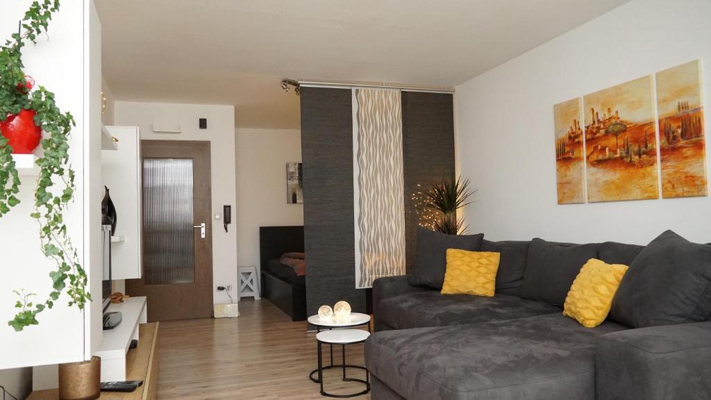 菲希特尔山区巴特贝内克Gemütliches Apartment in Bad Berneck的客厅配有灰色的沙发和黄色的枕头。