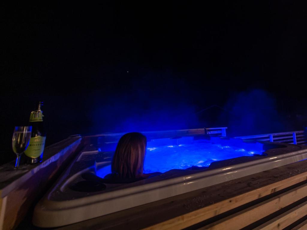 特罗姆瑟Arctic Lodge Tromvik with jacuzzi的坐在蓝色灯光的热水浴缸中的女人