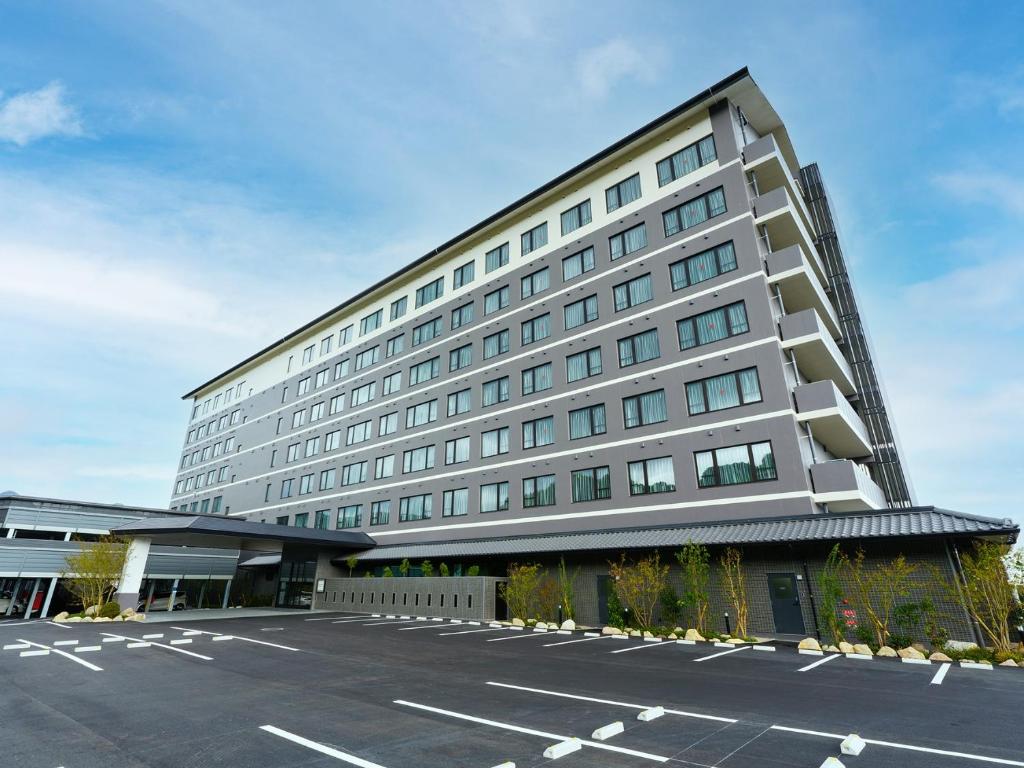 别府Grandvrio Hotel Beppuwan Wakura - ROUTE INN HOTELS -的一座大型建筑,前面设有停车场
